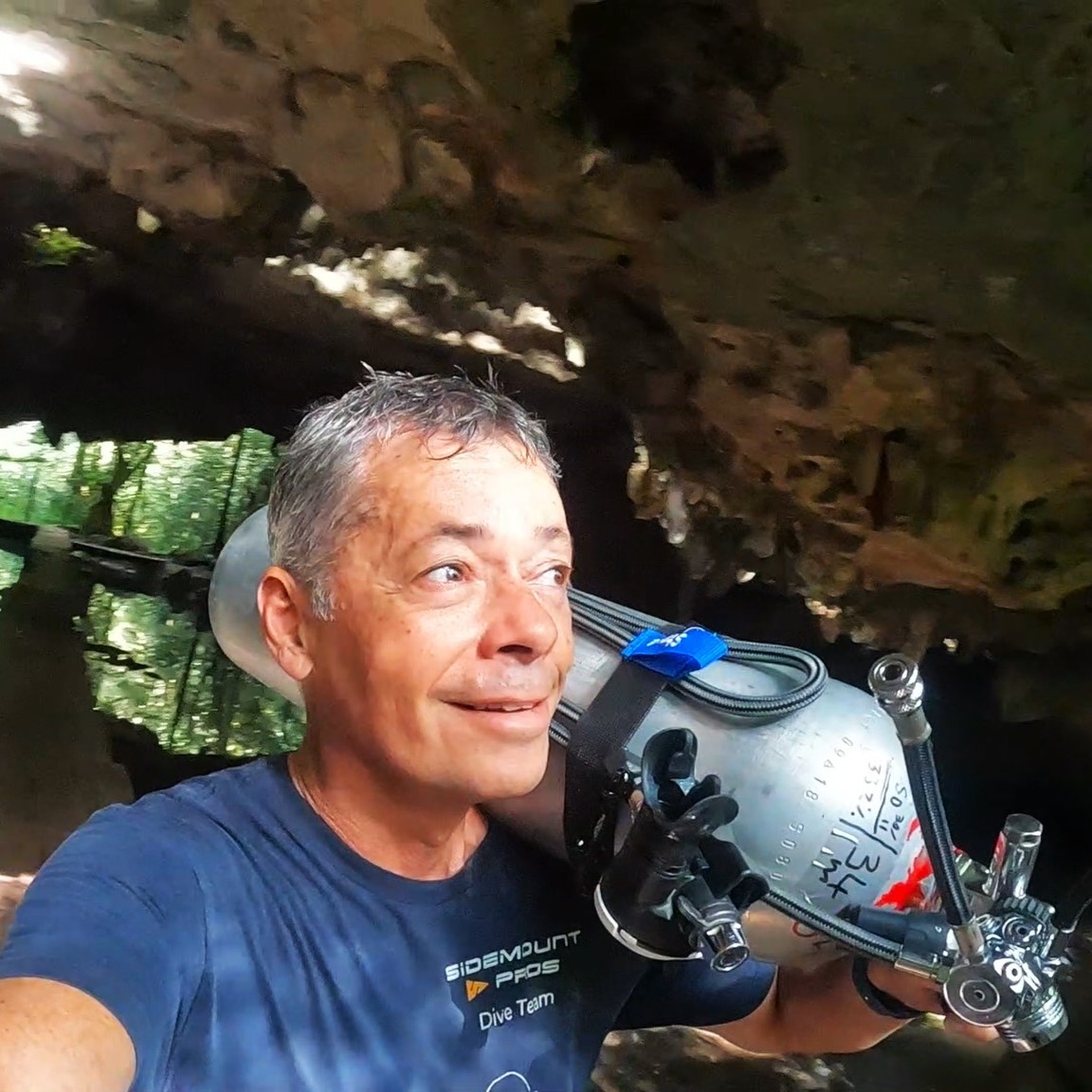 Steve Davis carrying his sidemount cylinders at a cave entrance